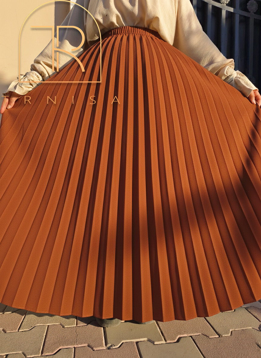 Brown pleated skirt being held up with 'ERNISA' branding.